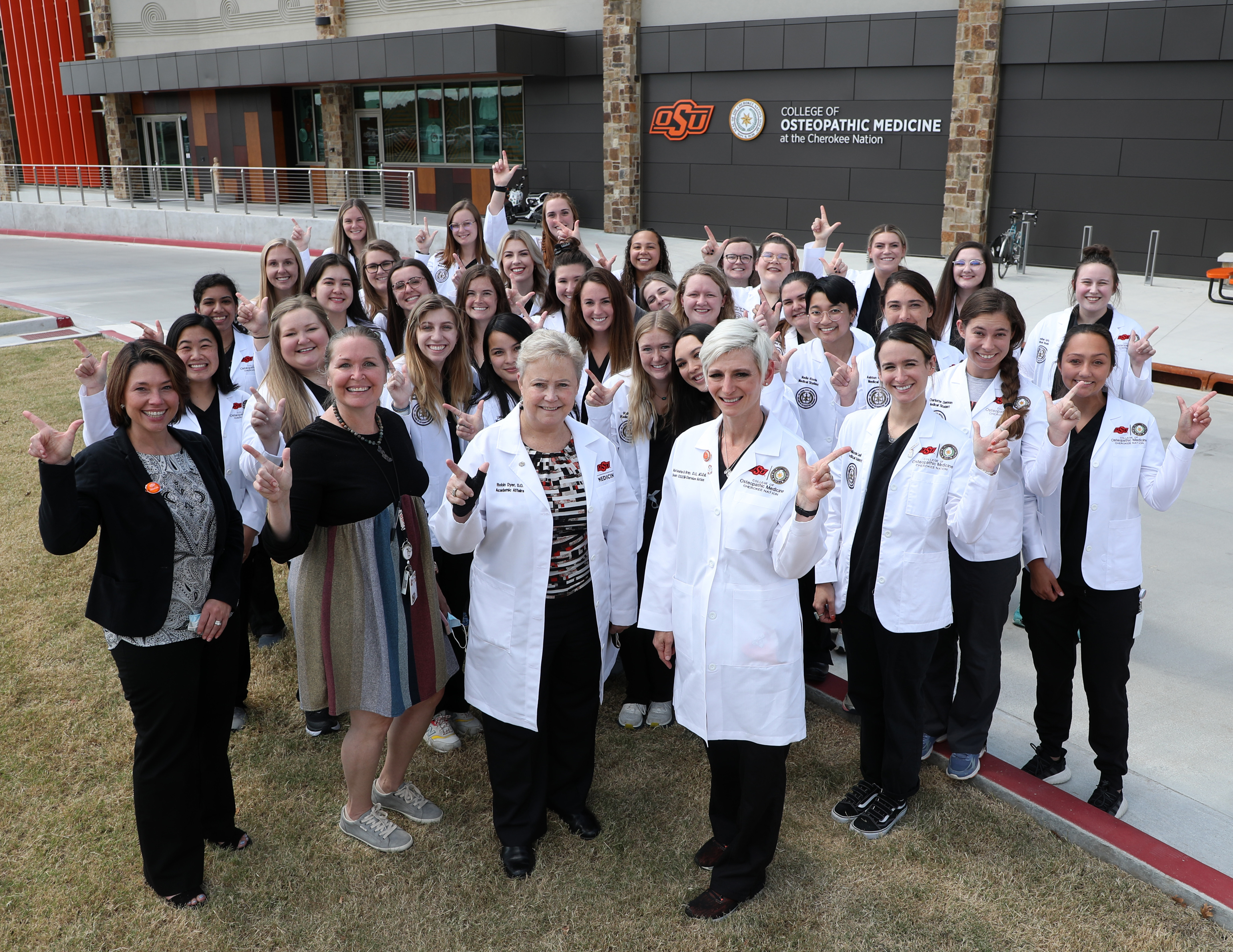 A group of faculty and students stand outside the Oklahoma State University College of Osteopathic Medicine at the Cherokee Nation