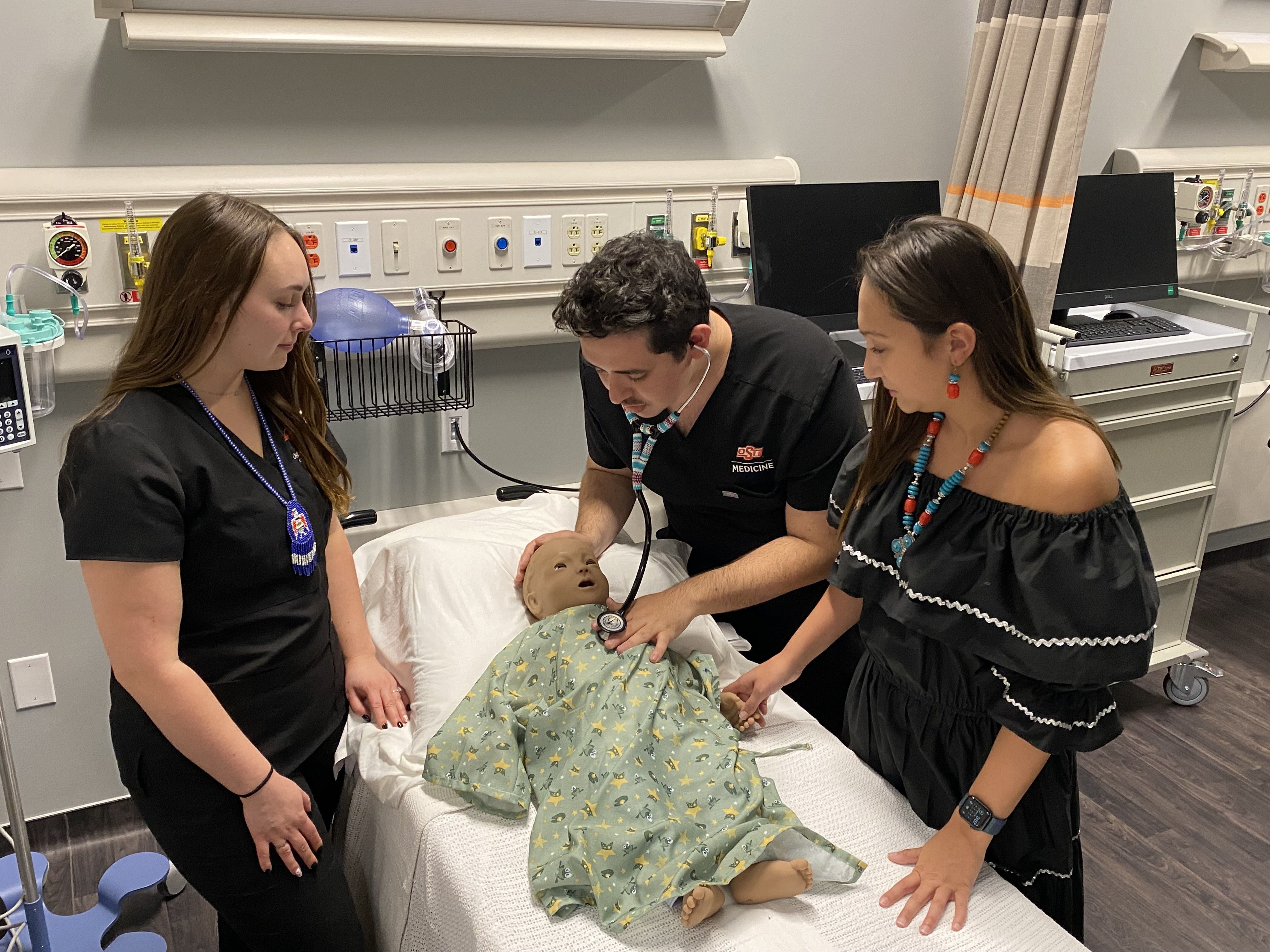 Three Indigenous medical students tending to a medical manikin