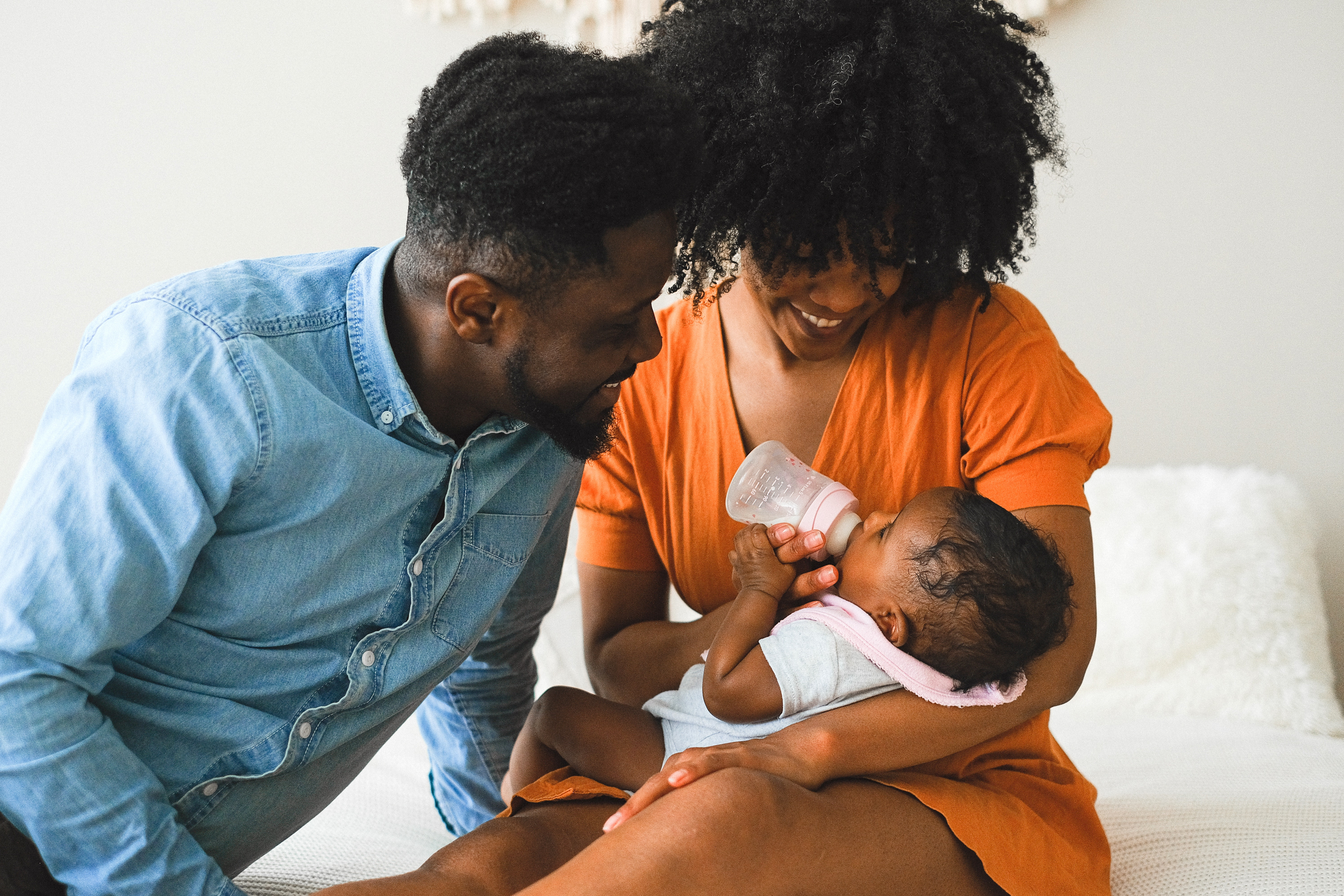 A couple looking at their infant while the mother feeds it a bottle