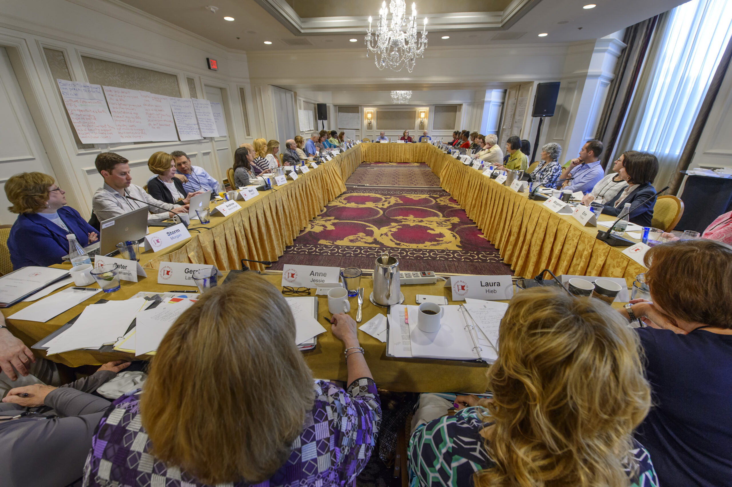 Photo of conference room with attendees gathered around a large rectangular table space