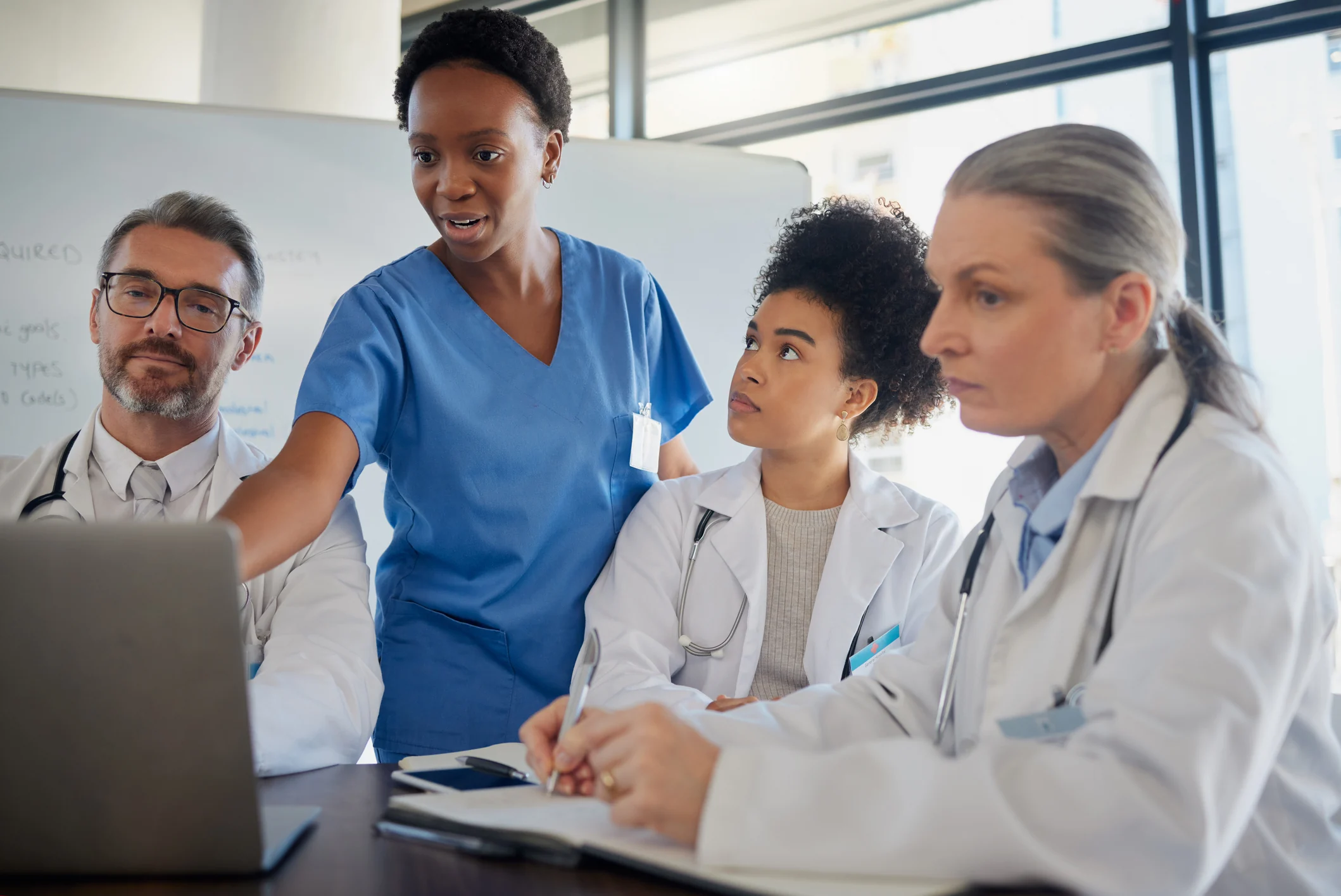 Team of medical professionals speaking near a laptop.